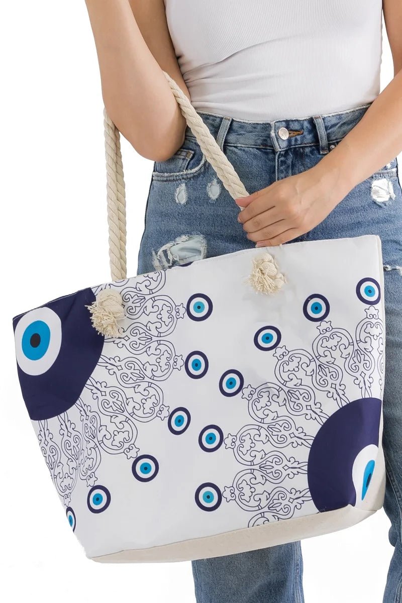 Lovely woman holding an evil eye tote bag with blue and white eye pattern at her hip