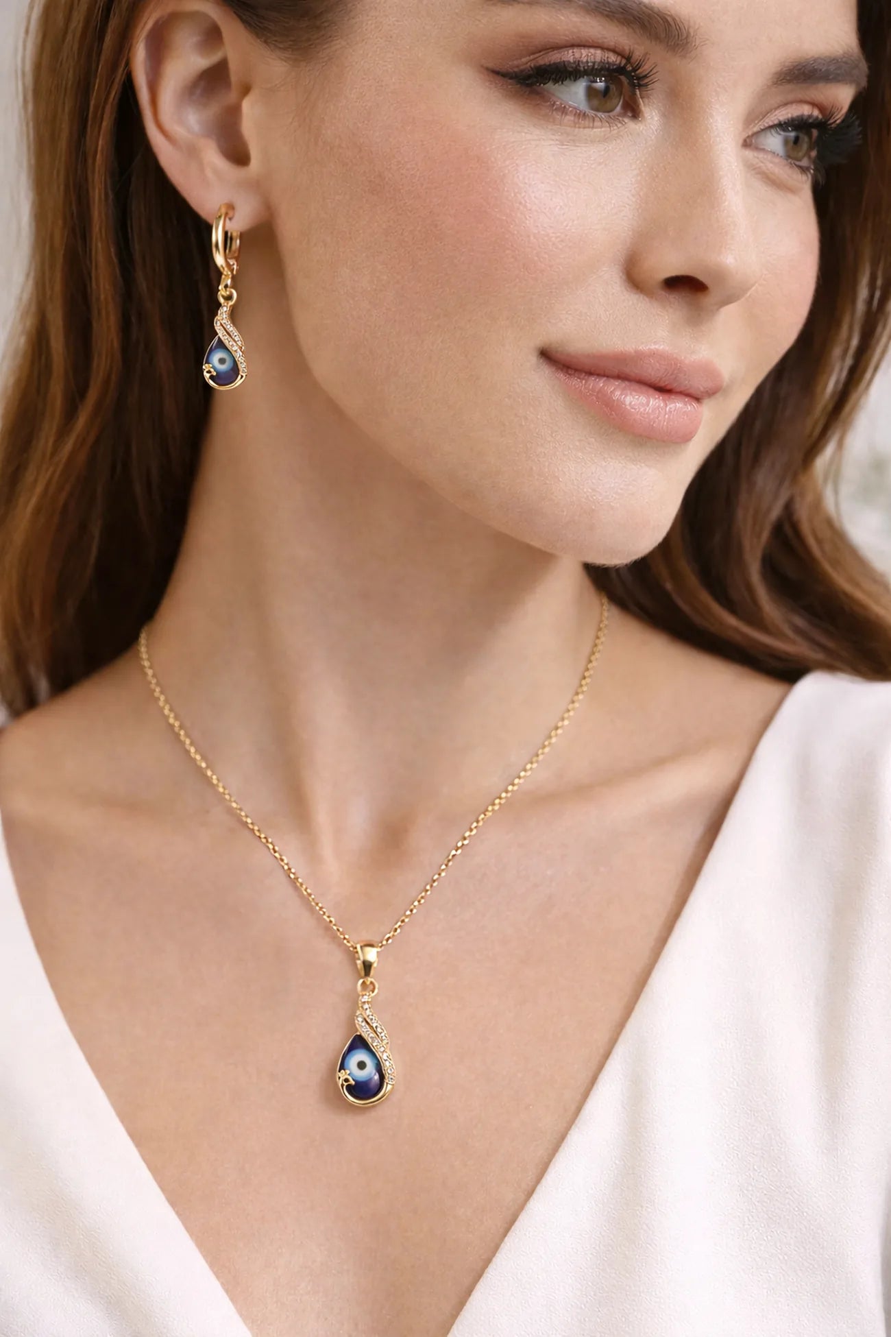 Woman wearing a gold necklace with a blue evil eye pendant and matching earrings