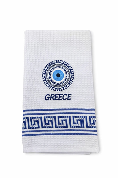 White towel with blue decorative elements, including a 'Mati' evil eye and 'Greece' text on a white background