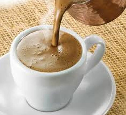 Coffee being poured into a white cup on a textured surface