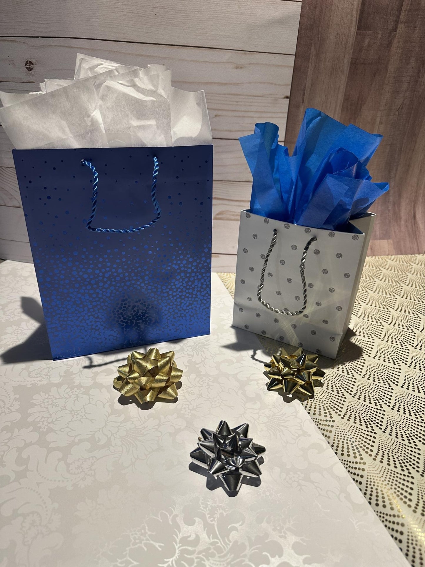 Blue and silver gift bags with decorative bows on a textured surface.