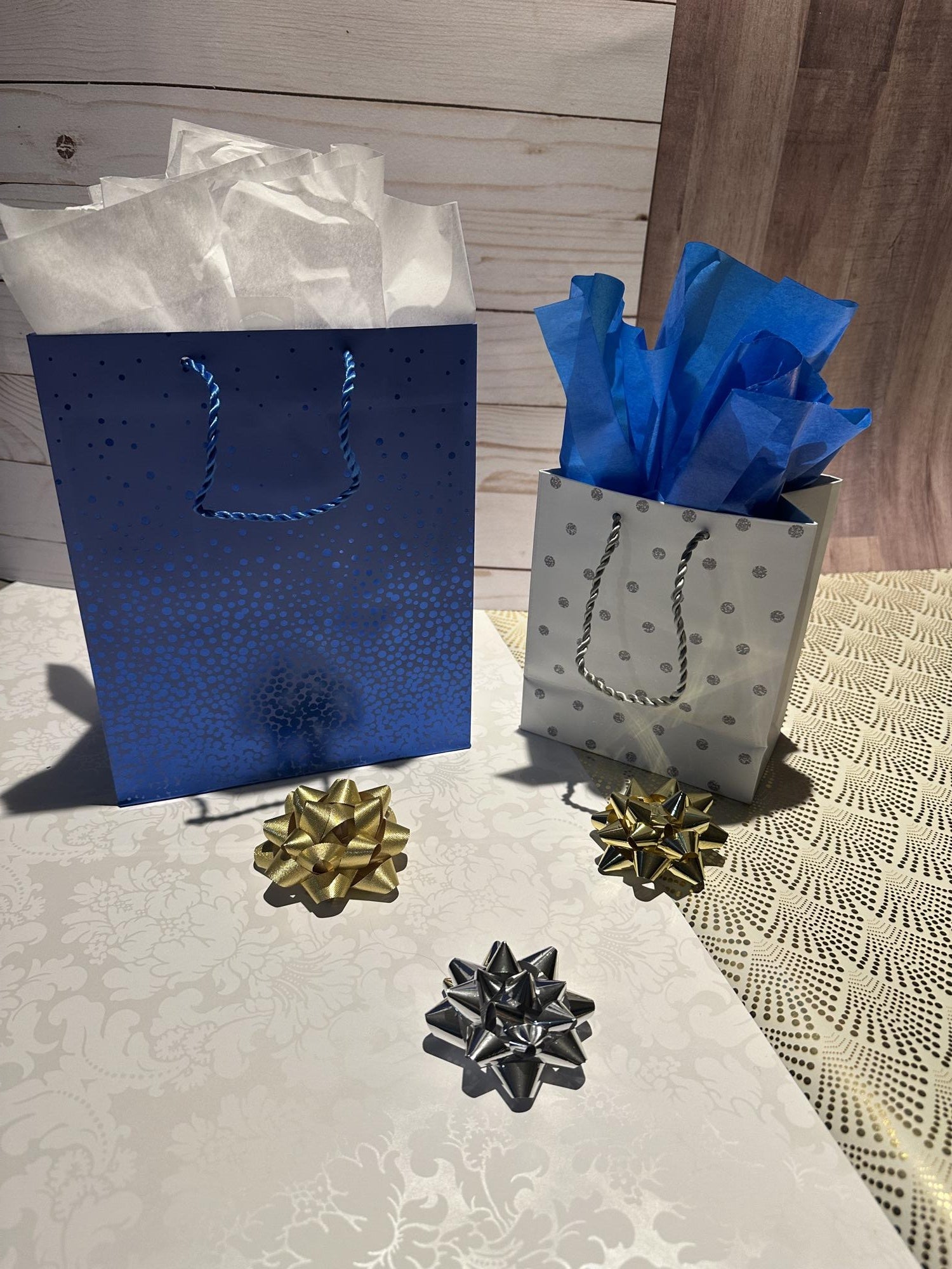 Blue and silver gift bags with decorative bows on a textured surface.