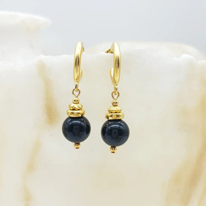 Gold earrings with black onyx beads on a white background