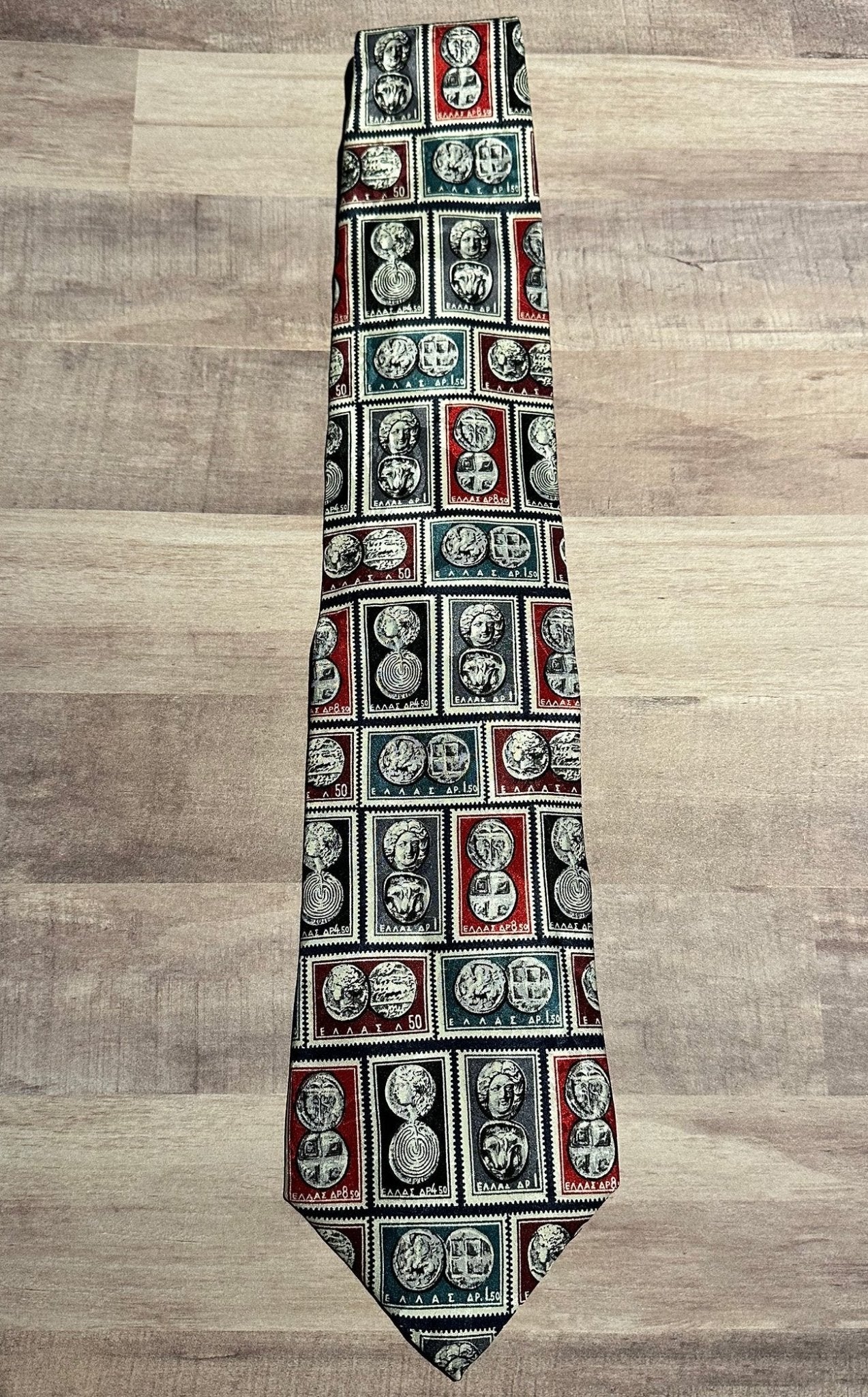 Close-up of a tie with a pattern of Greek stamps with ancient Greek coins in rectangles on a wooden surface