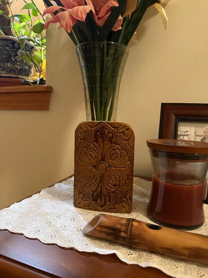 Front of decorative wooden religious icon diptych with a vase of flowers and a candle on a lace tablecloth