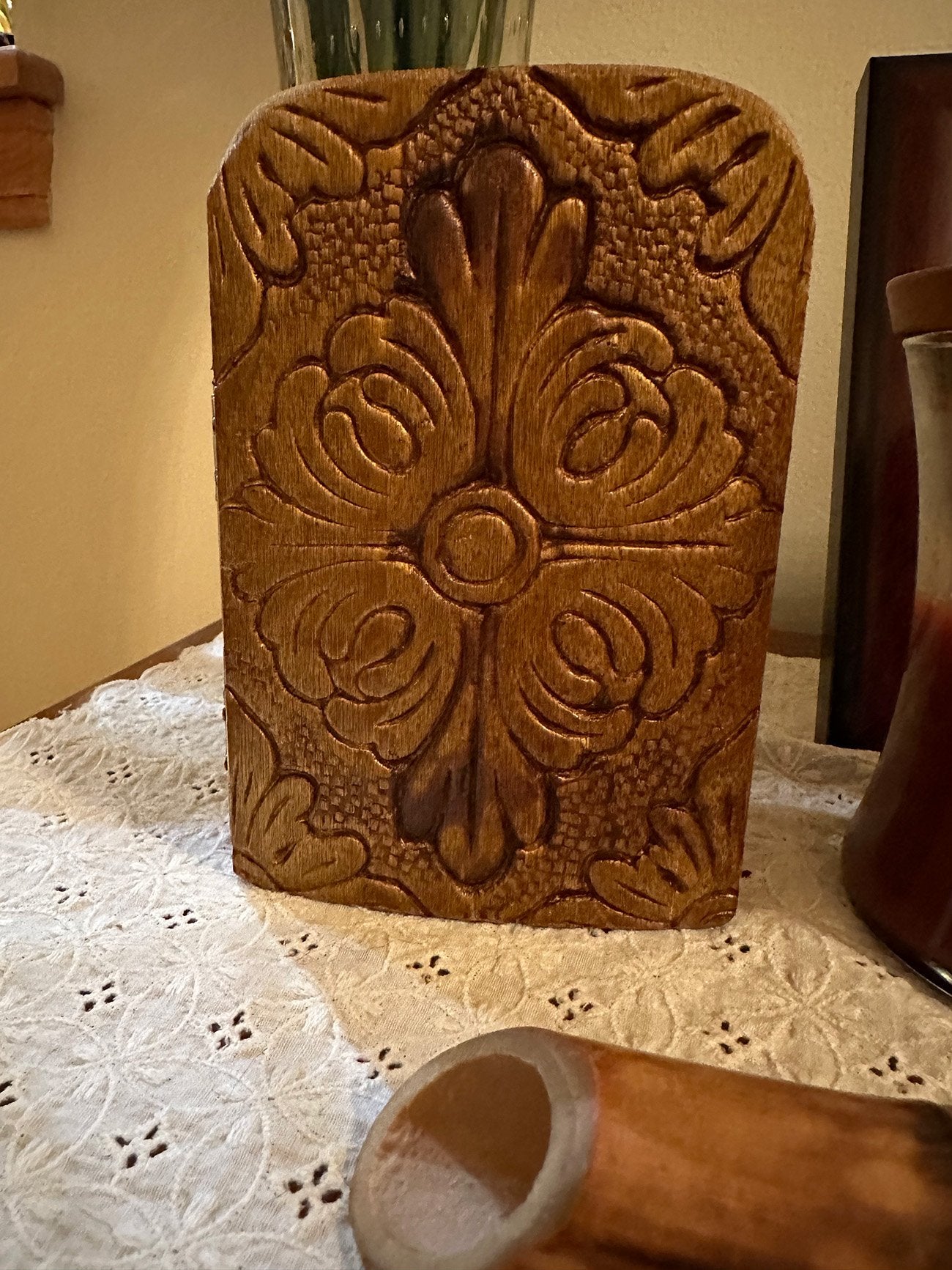 Front of wooden religious icon diptych with intricate design on a lace tablecloth