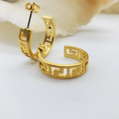 Gold Greek meander design hoop earrings on a white background