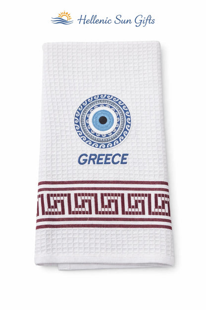 White waffle weave cotton dish towel with Greek evil eye design and 'GREECE' in text with a Greek key design on a white background