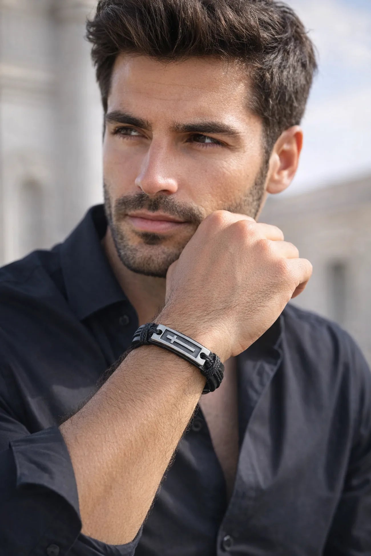 Handsome man wearing black leather bracelet with silver cross and black button down shirt