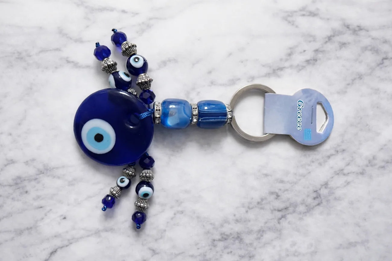 Decorative keychain with blue evil eye charm on a marble surface