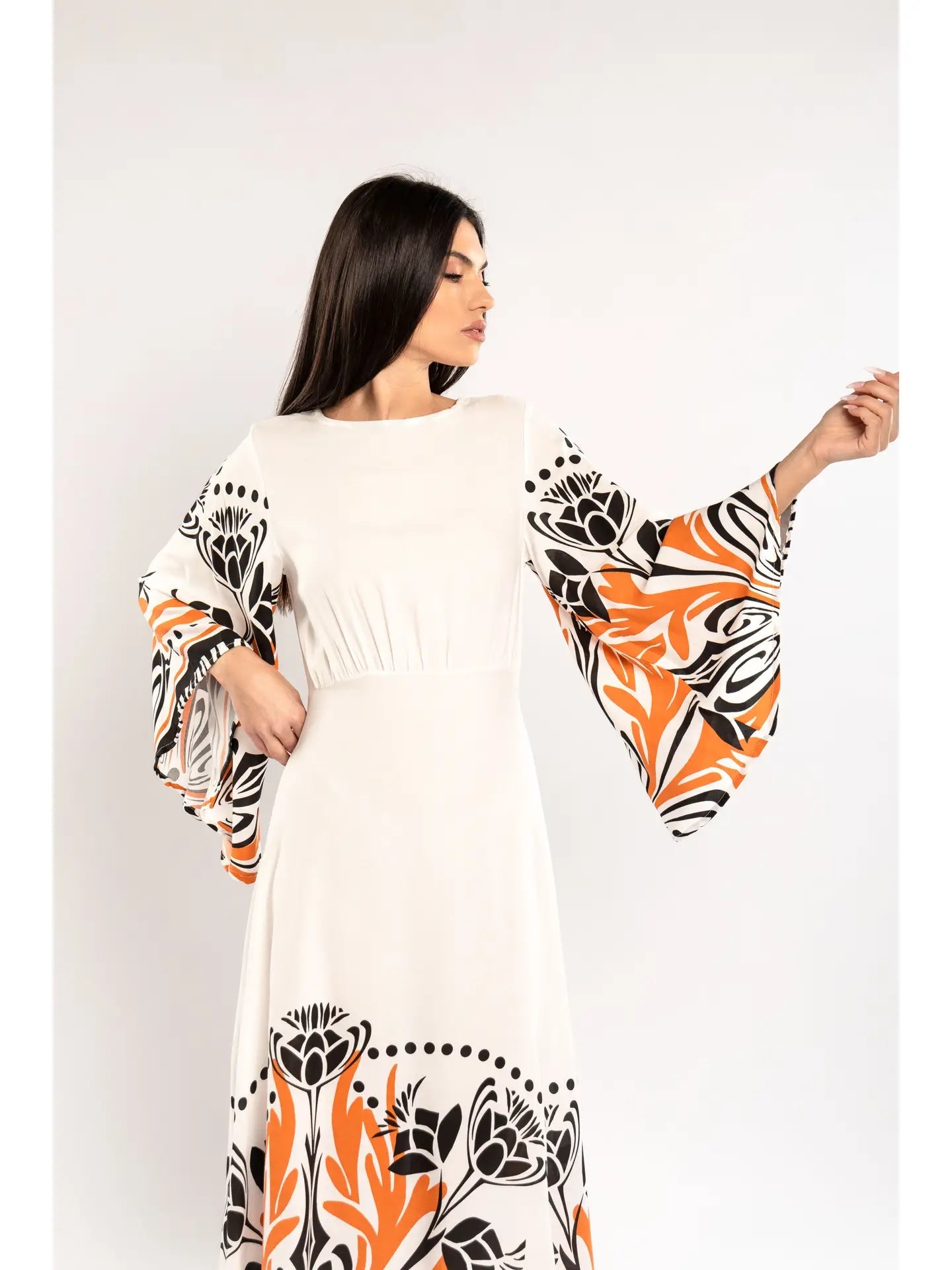 Woman wearing a white dress with orange and black floral patterns on a white background - facing left