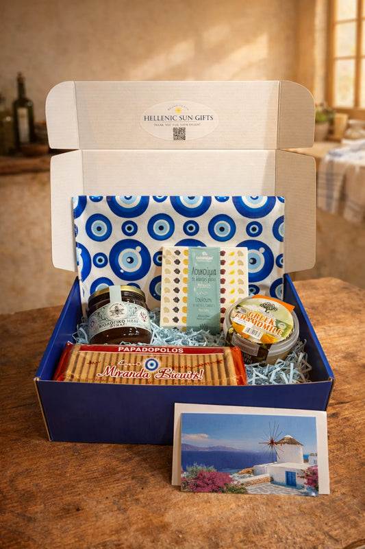 Gift box with Greek-themed products including a jar, cookies, and a card on a wooden table.