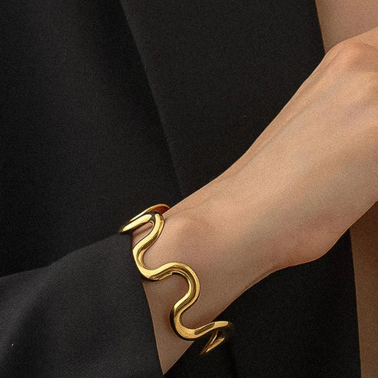 Gold swan-shaped bracelet on a wrist against a black background