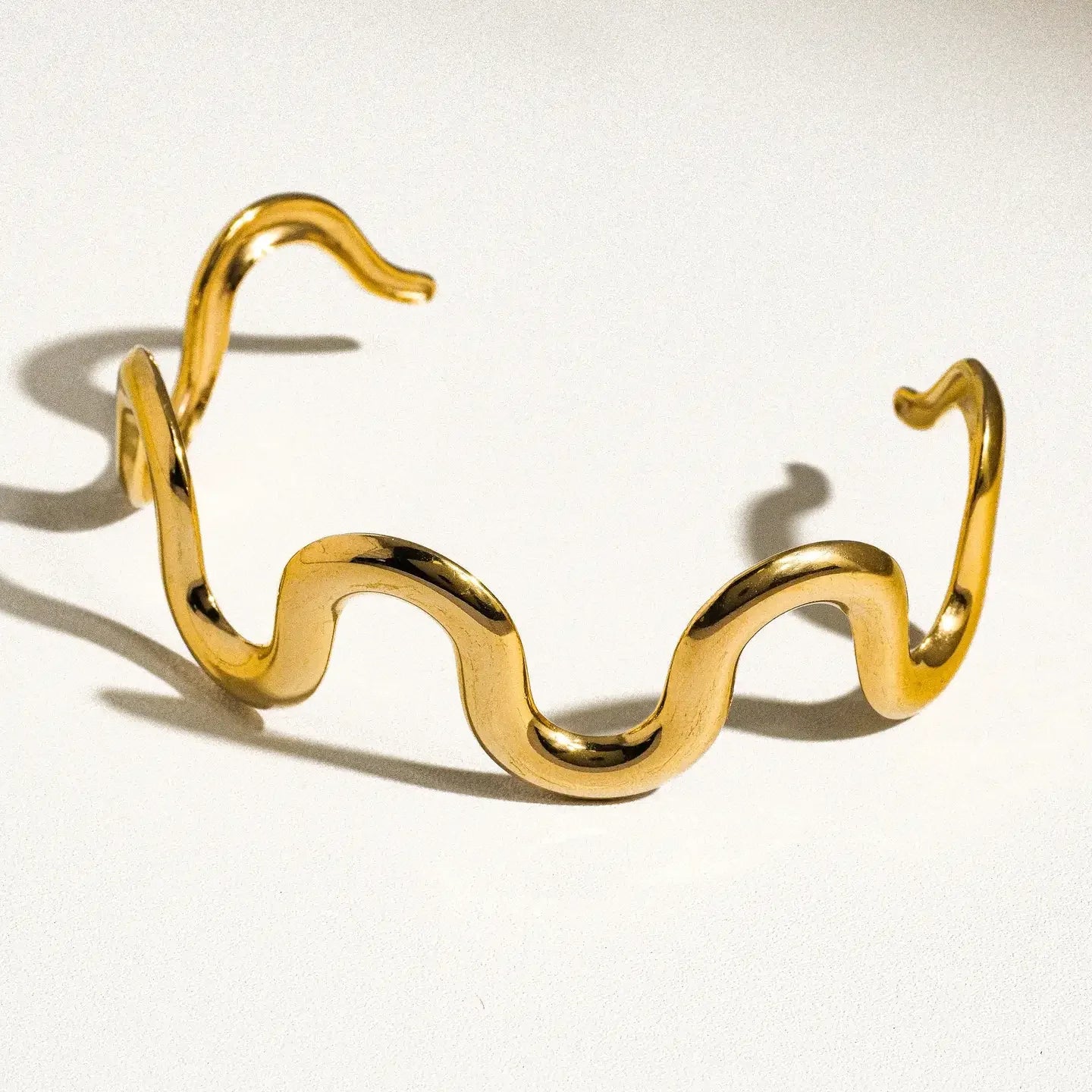 Gold wavy bracelet on a white background
