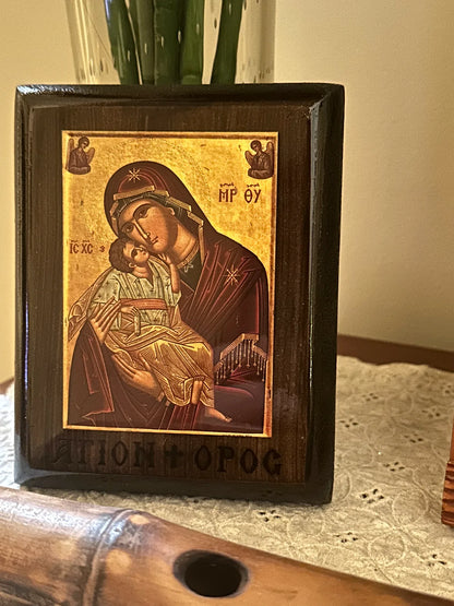 Framed religious icon of a woman holding a child on a table.