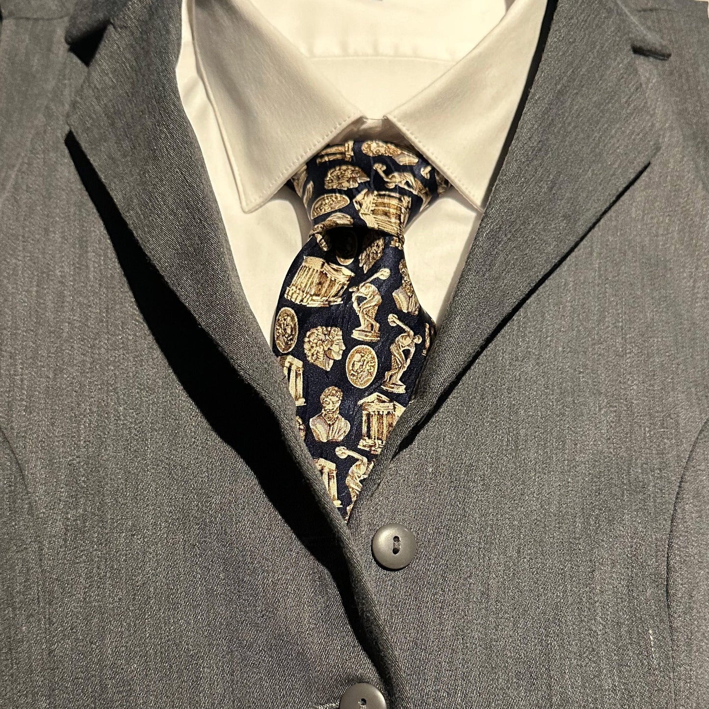 Close-up of a gray suit with a Greek architecture and sculpture patterned tie