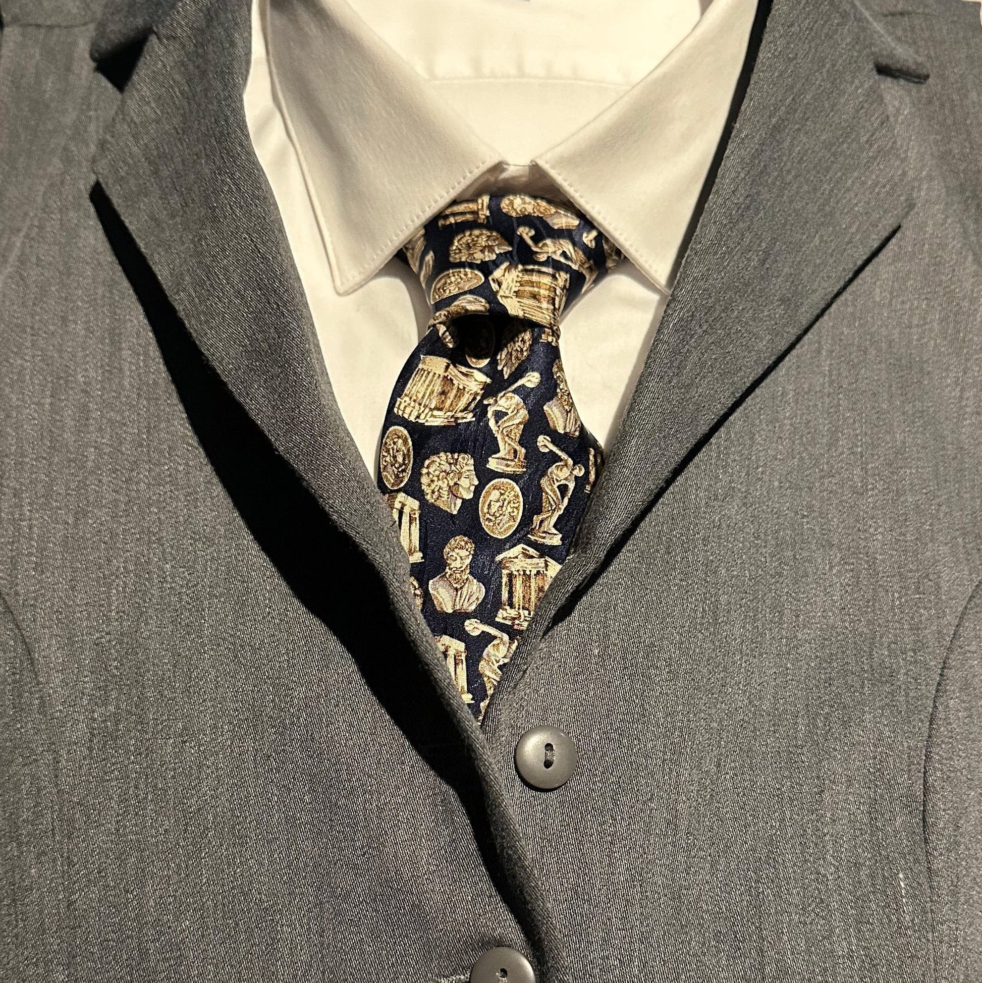 Close-up of a gray suit with a Greek architecture and sculpture patterned tie