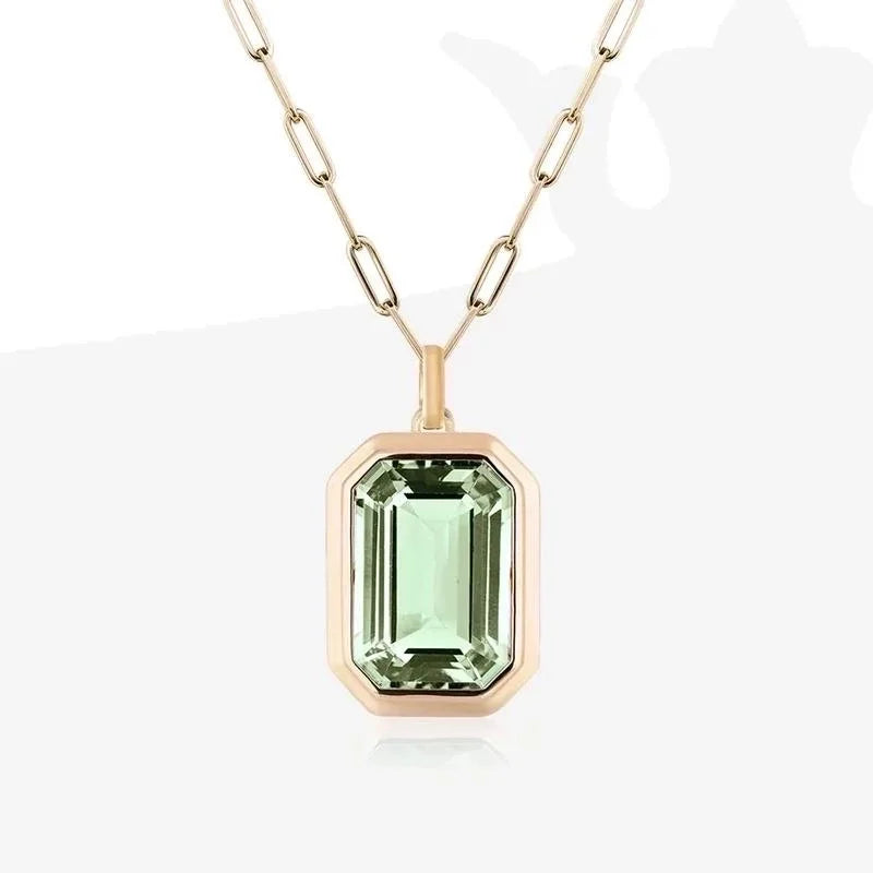 Green emerald cut stone in gold clip necklace on a white background