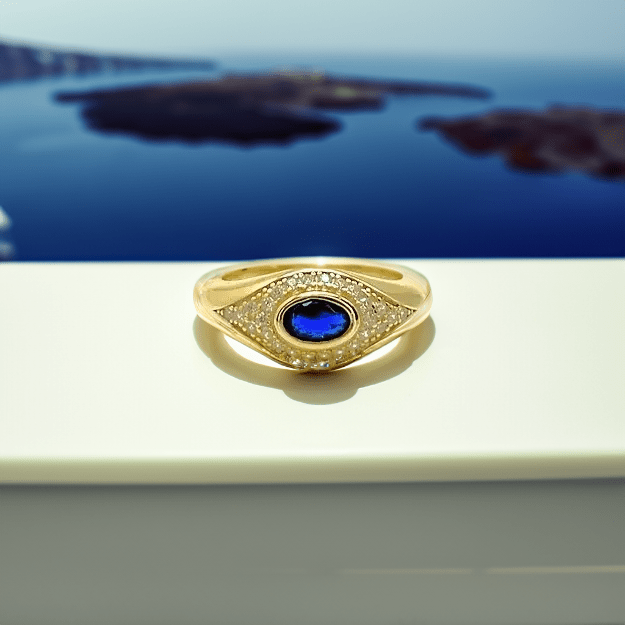 Gold ring with a blue gemstone on a reflective surface