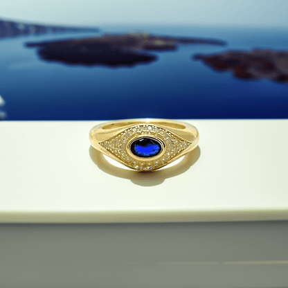 Gold ring with a blue gemstone on a reflective surface