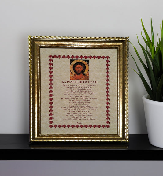 Framed artwork with religious Greek text and icon on a shelf with a plant