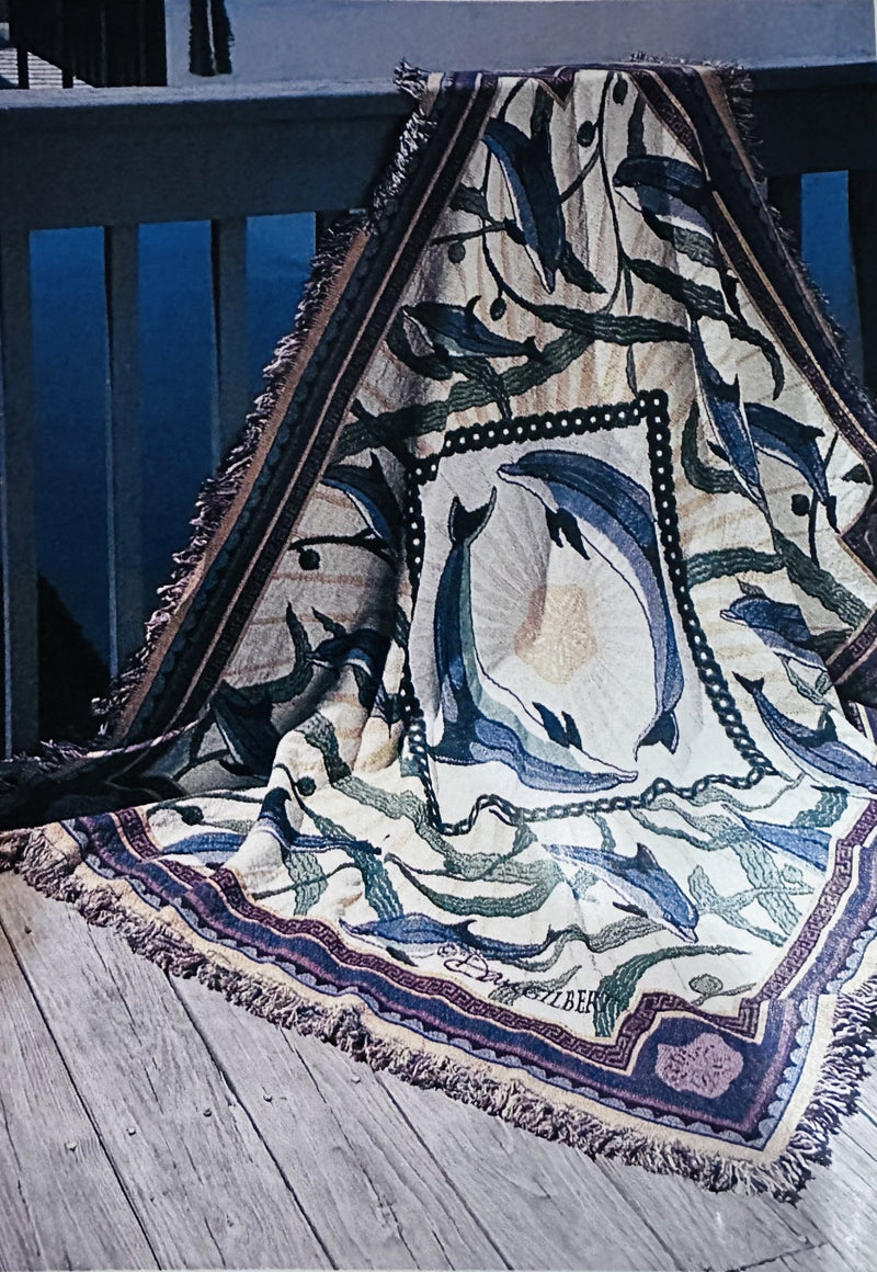 Decorative throw blanket with dolphin design on a wooden surface