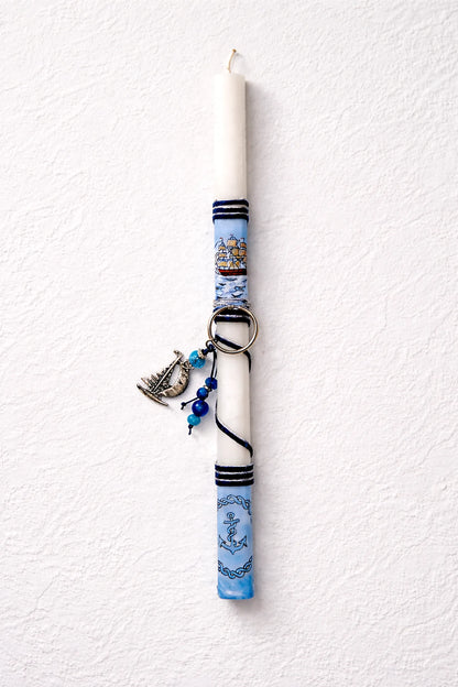 Decorative candle with blue and white pattern and charms on a textured white background