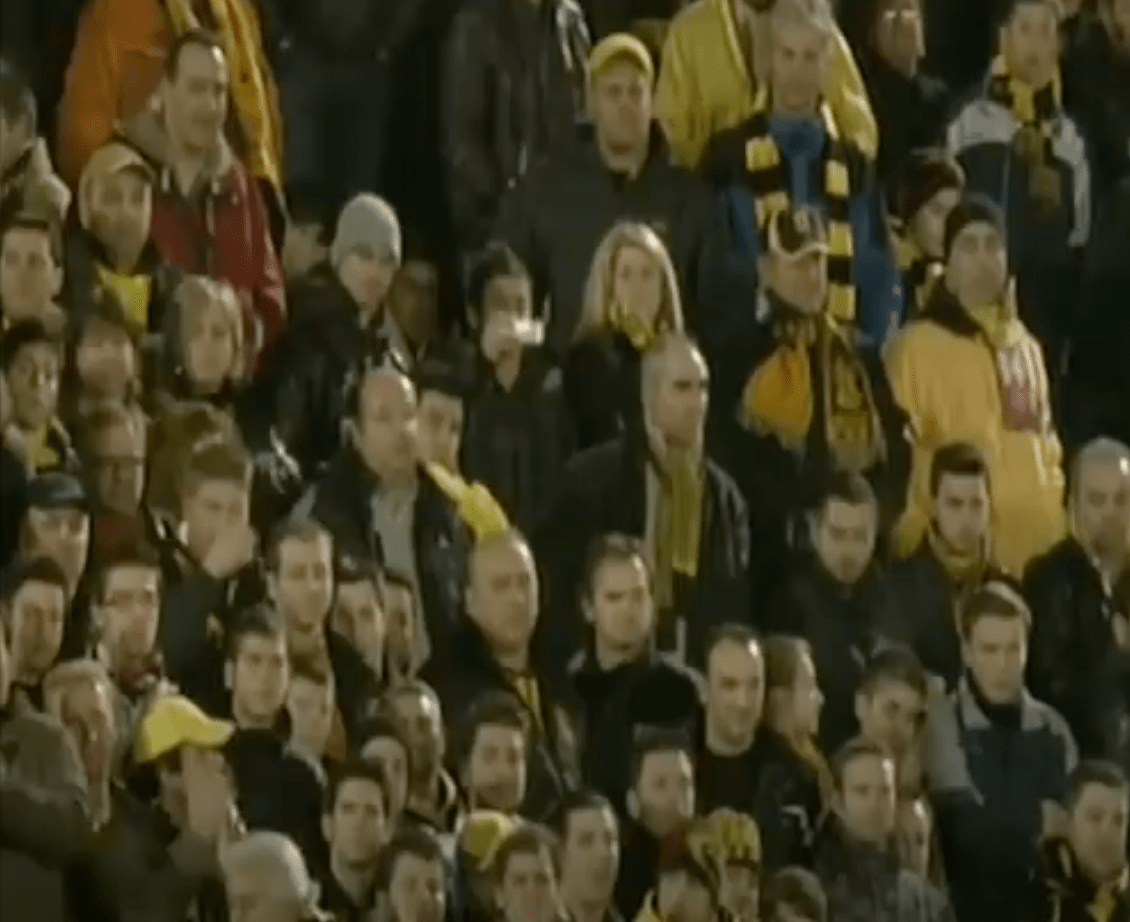 Spectators in a stadium with yellow and black clothing, fans of Salonika AS Aris soccer team