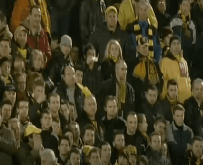 Spectators in a stadium with yellow and black clothing, fans of Salonika AS Aris soccer team