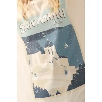 Front of blond woman wearing a distressed graphic tee with "Santorini Greece" and scenes of the domed churches and sea on a beige background