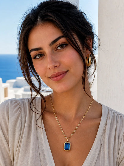 Woman wearing a gold necklace with a blue pendant outdoors