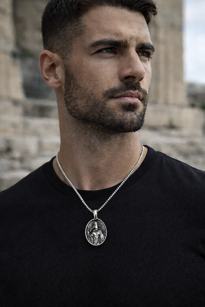 Man wearing a necklace with a pendant in front of stone architecture